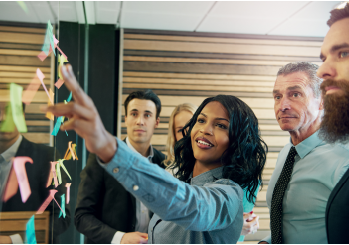 A woman pointing at a large computer monitor with her colleagues looking on