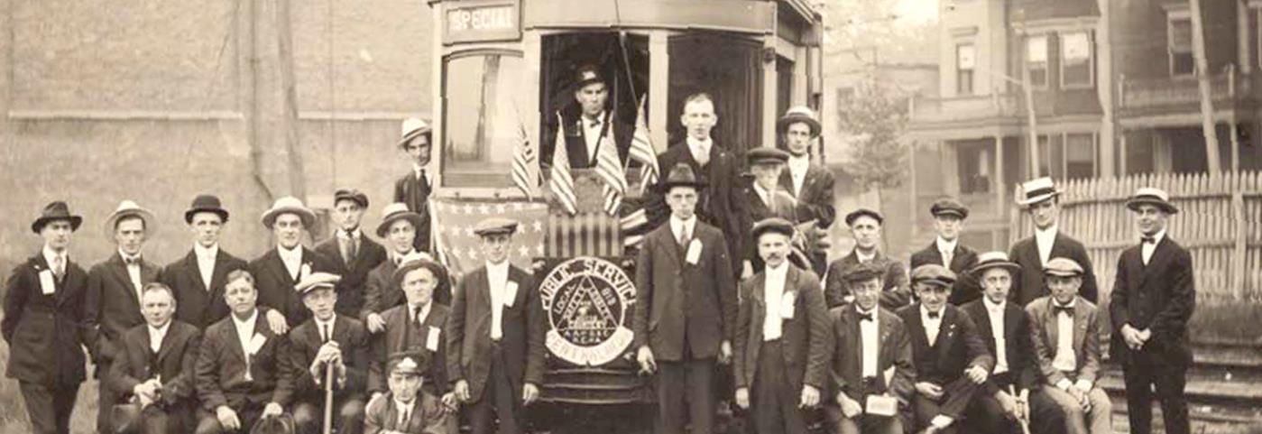 Public Service workers posing for a picture in front of a trolley
