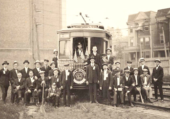 Public Service workers posing for a picture in front of a trolley