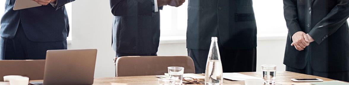 Company executives standing around a conference room table.