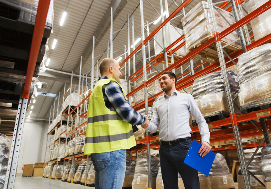 Two people shaking hands inside a supply warehouse