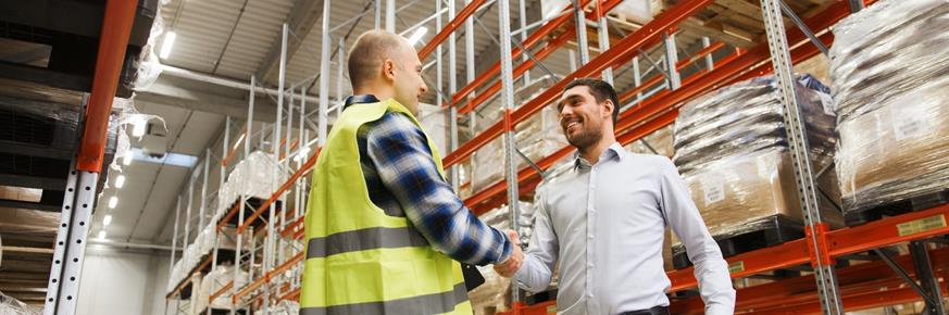 Two people shaking hands inside a supply warehouse